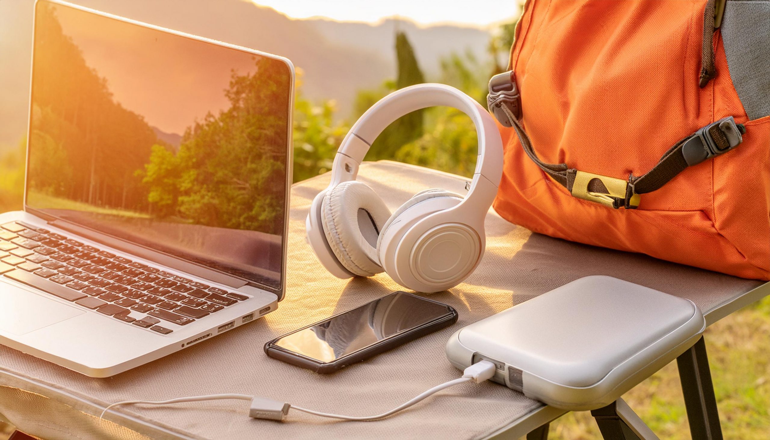 Illustration showcasing essential items for digital nomads, including a laptop, power bank, wireless headphones, travel backpack, and compact standing desk.