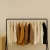 Elegant clothing display with neutral-toned garments and a brown handbag